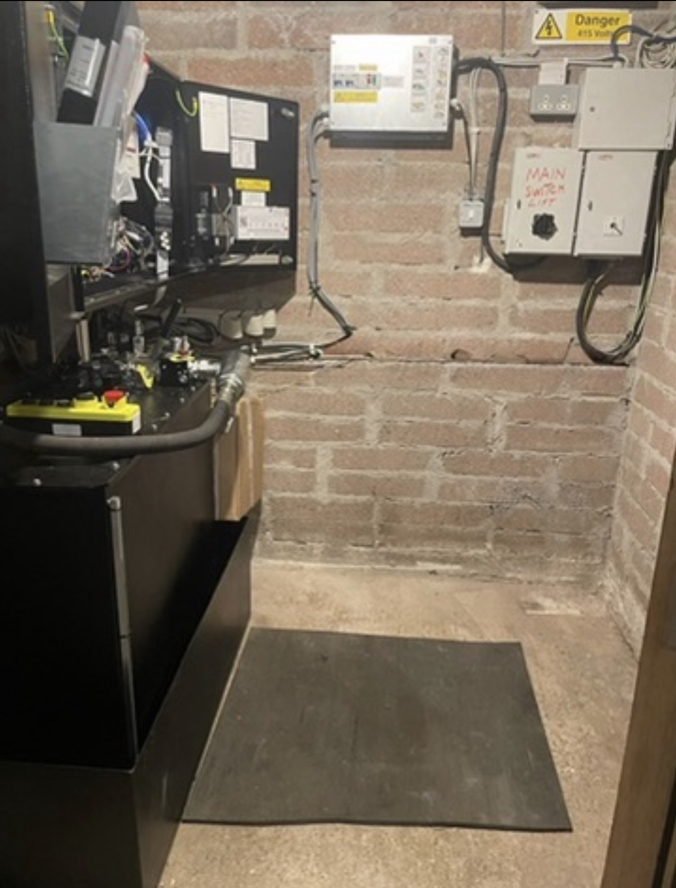 Lift machinery and wall-mounted electrical controls in a brick-walled room